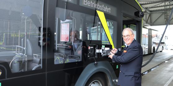 OB Keck steht am EBus und steckt den Ladestecker in den Bus