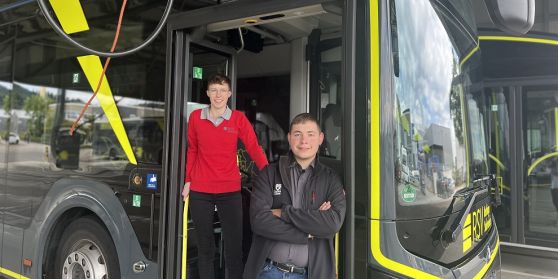 Die zwei frischgebackenen Berufskraftfahrer der RSV stehen an einem Elektrobus