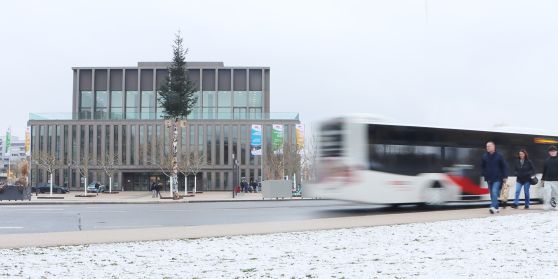Ein Bus der RSV fährt durch den Schnee. Im Hintergrund ein Tannenbaum vor der Stadthalle.