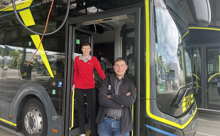 Die zwei frischgebackenen Berufskraftfahrer der RSV stehen an einem Elektrobus